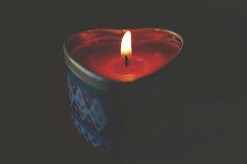 Heart-shaped candle with warm, glowing flame creating a romantic atmosphere.
